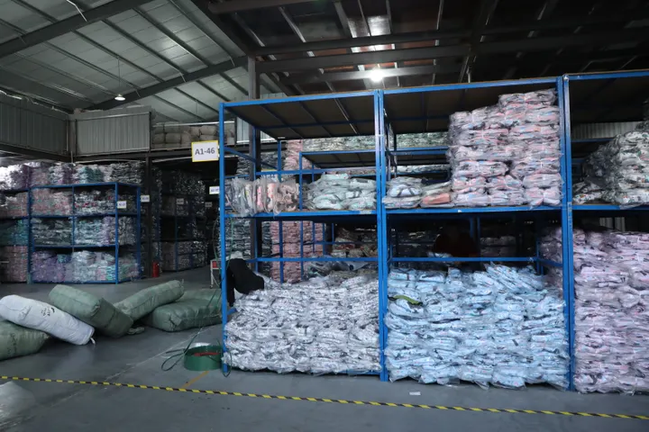 Racked poly-bagged finished backpacks in the Senszx warehouse, labelled by bay and ready for cartoning